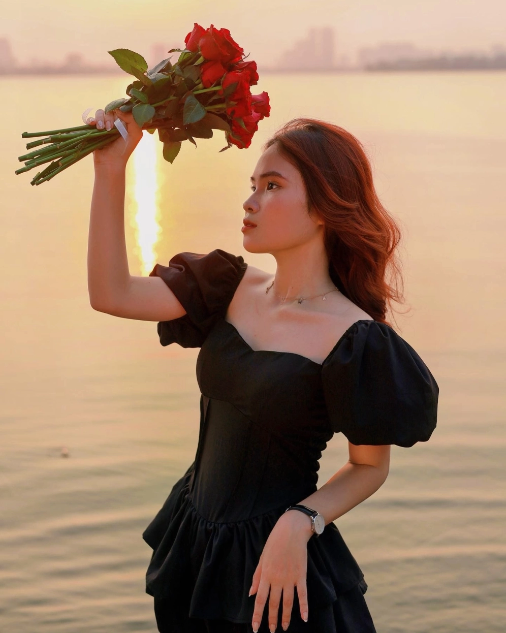 Cô gái đứng ngắm mặt trời lặn trên đỉnh núi cao lộng gió